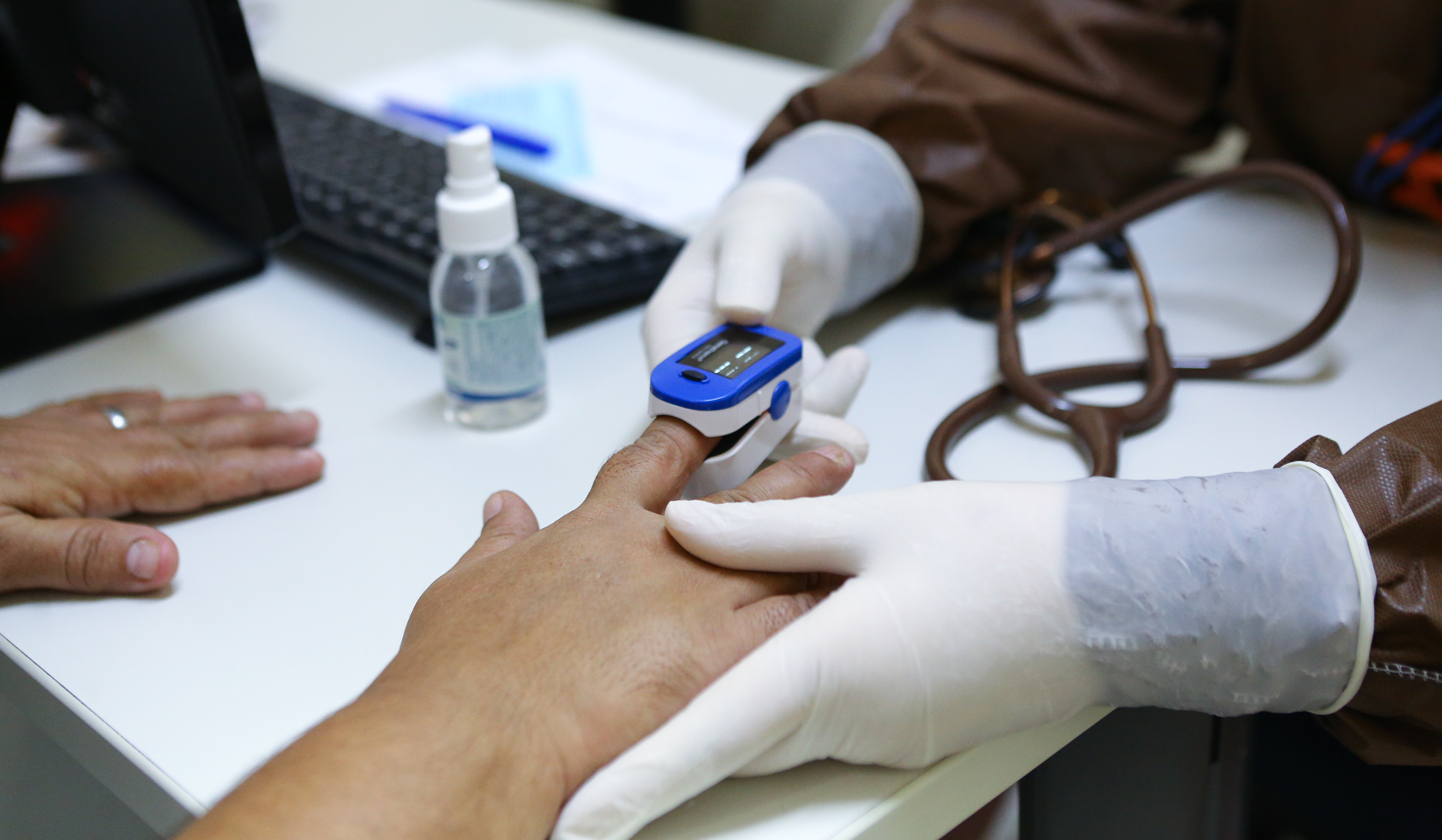 enfermeira coloca um oxímetro no dedo de um paciente